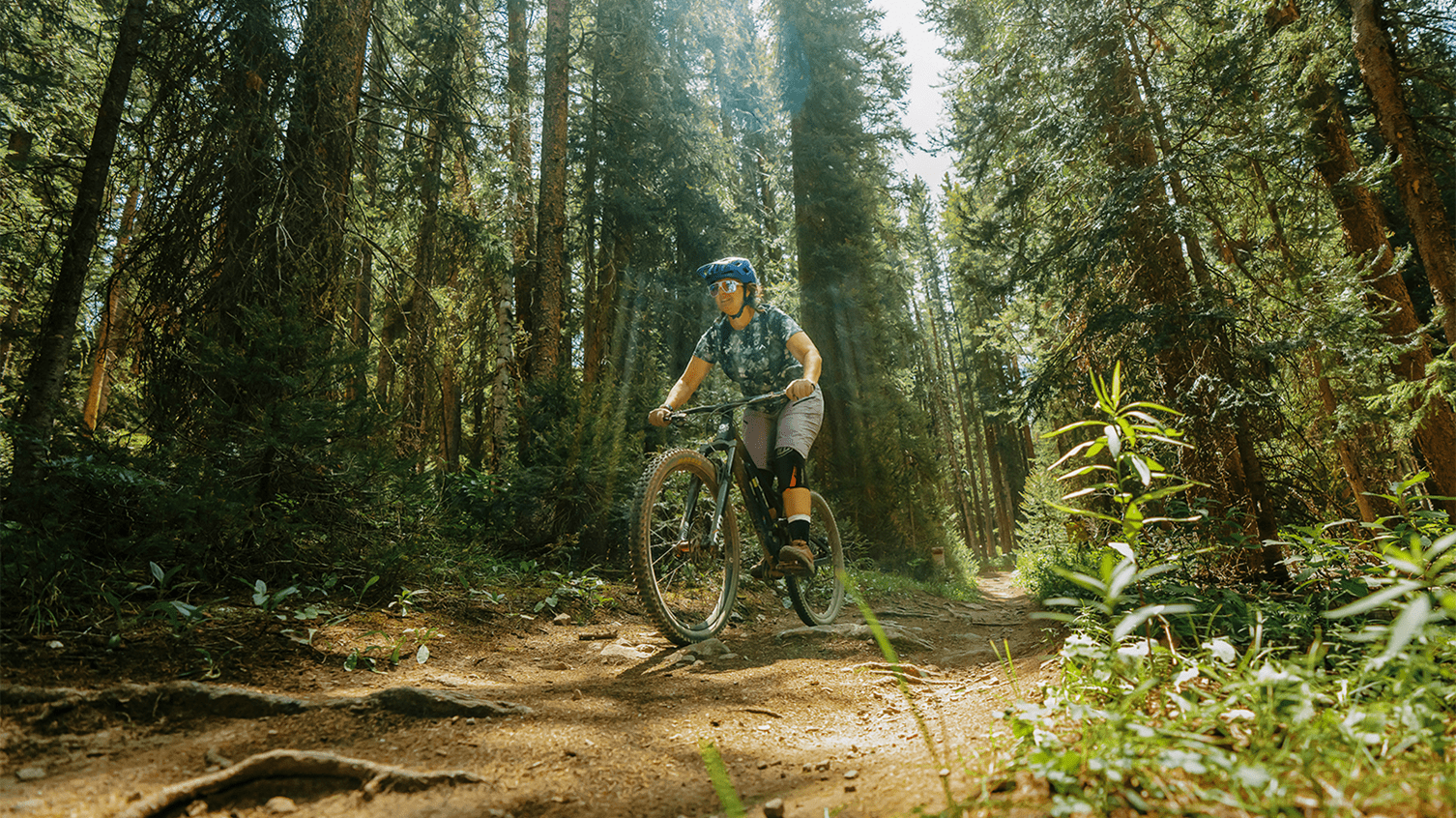 Female biker rides through forest 