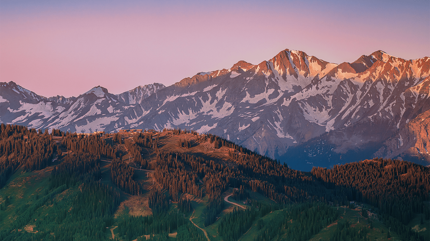View of Aspen Mountain at dusk, with a purple glow, during the summer
